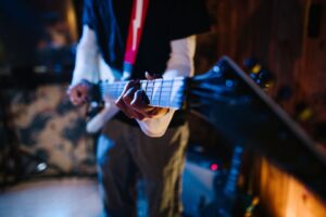 Nahaufnahme eines E-Gitarristen beim Spielen auf einer dunklen Clubbühne